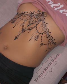 a woman laying on top of a bed with her stomach covered in hendi tattoos