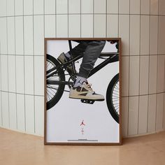 a poster hanging on the wall above a pair of feet riding a skateboard in front of a white tiled wall