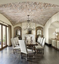 a dining room with a chandelier hanging from the ceiling and chairs around it