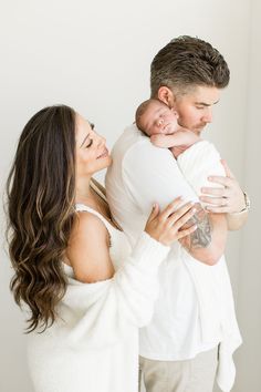 a man and woman holding a baby in their arms