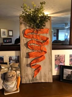 a wooden sign with carrots tied to it and some pictures on the wall behind it