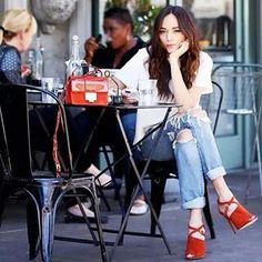 a woman sitting at an outdoor table with her hand on her chin and looking to the side