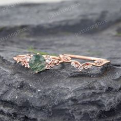 a close up of a ring on top of a rock with an emerald stone in the middle