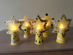 five yellow stars with lights on them sitting on a table next to each other in front of a white wall