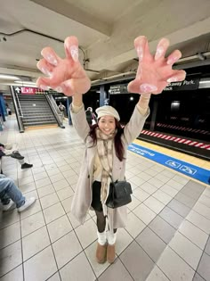 a woman holding her hands up in the air while standing on a tile floor at an airport