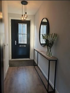 a hallway with a black door and a mirror on the wall next to a table