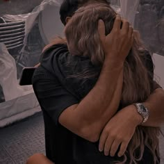 two people hugging each other in front of a window