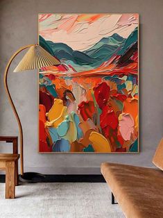 a painting hanging on the wall next to a chair and lamp in a living room