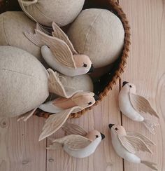 some birds are sitting in a basket on the floor next to three eggs that have been made from felt