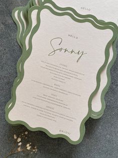 the wedding stationery is laid out on top of each other, with green and white lettering