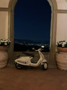 a scooter is parked in front of an arch with flowers on the windowsill