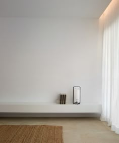 a minimalist white room with books on the shelf