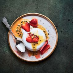 a plate topped with yogurt and strawberries on top of a green table