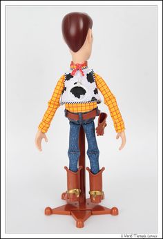 a toy doll with a cowboy outfit and boots on it's legs, standing on a wooden stand