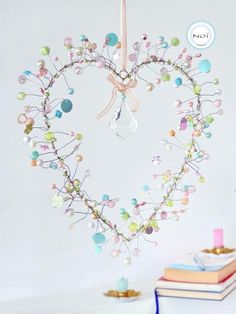 a heart - shaped decoration hanging from a string with beads and pearls on it, next to some books