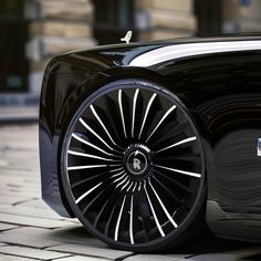 a black car with white spokes is parked on the street