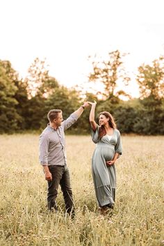 a pregnant couple holding hands in a field