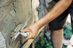 a man is using a pair of scissors to work on a wall that has been made out of concrete