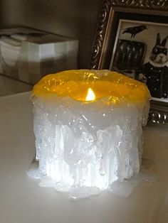 a lit candle sitting on top of a white table next to a framed photo and a mirror