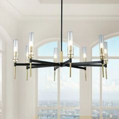 a chandelier hanging from a ceiling in a room with large windows overlooking the city