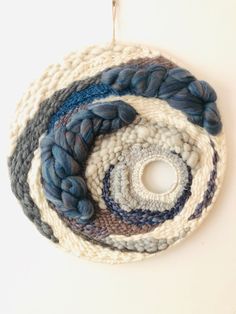 a crocheted circular ornament hanging from a hook on a white wall