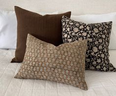 four pillows on a bed with white sheets and brown pillow cases in the middle one