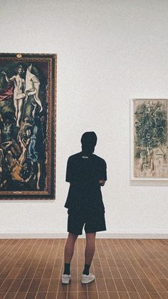 a person standing in an art gallery looking at paintings