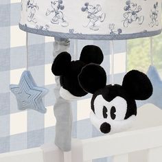 a mickey mouse lamp hanging from the side of a crib