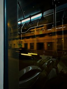 the reflection of a subway car and its lights are seen in the glass window as it passes by