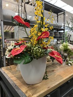 a large white vase filled with flowers on top of a wooden table in a store