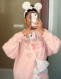 a woman taking a selfie in front of a mirror wearing minnie mouse ears and pink sweatshirt