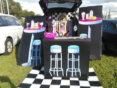 a black and white checkered table with blue stools in front of an outdoor bar