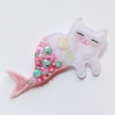 a white cat with pink and green sequins on it's tail laying down