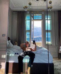 a man taking a selfie in his bedroom with a mirrored wall and chandelier hanging from the ceiling