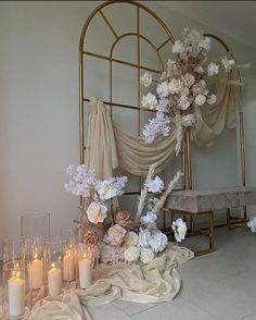 a table topped with lots of white flowers and lit candles next to a gold frame