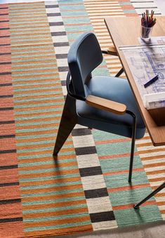 a chair sitting on top of a rug next to a table with a pen and pencil