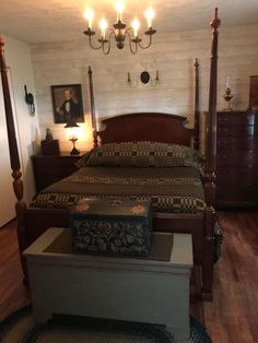 a bedroom with a bed, dresser and chandelier