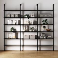 a book shelf with many books and plants on it in an empty room next to a white wall