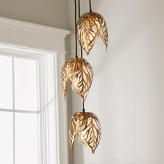 three lights hanging from the ceiling in front of a window with white walls and windowsill