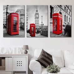 three red telephone booths in front of a white couch and wall with black and white pictures on it