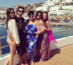 four people standing on a boat posing for a photo with the water in the background