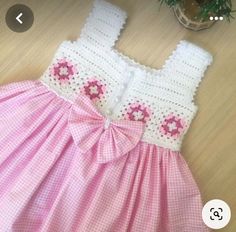 a pink and white dress sitting on top of a wooden floor next to a potted plant