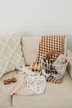 a white basket filled with baby items sitting on top of a couch next to a pillow