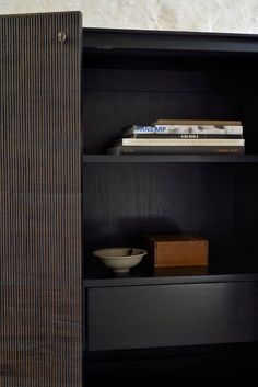 a book shelf with books and bowls on it