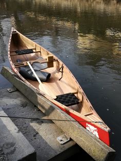 a small wooden boat sitting on top of a lake next to a dock with an oar