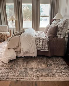 a large bed sitting in the middle of a living room next to a window with curtains