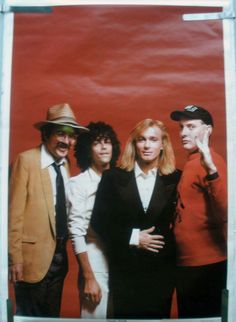 a group of people standing next to each other in front of a red wall with a white frame