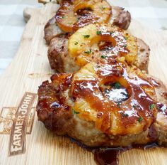 two pieces of meat covered in sauce on a cutting board