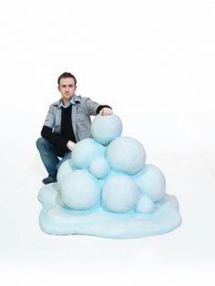 a man is sitting on top of an iceberg with balls in the shape of snow