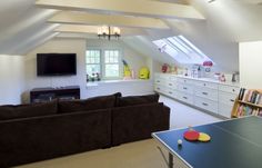 a living room filled with furniture and a ping pong table in front of a flat screen tv